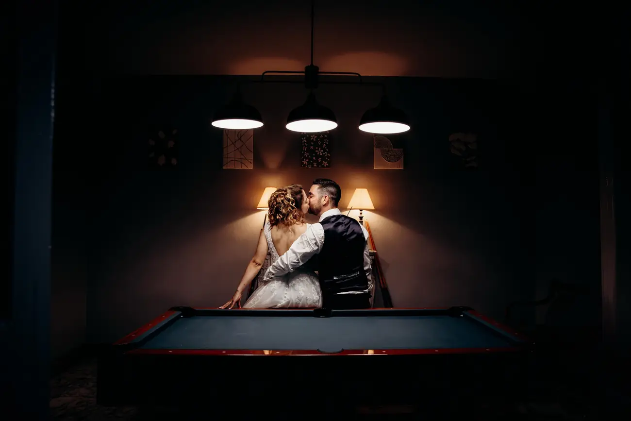 Baiser des mariés près d'un billard, ambiance tamisée